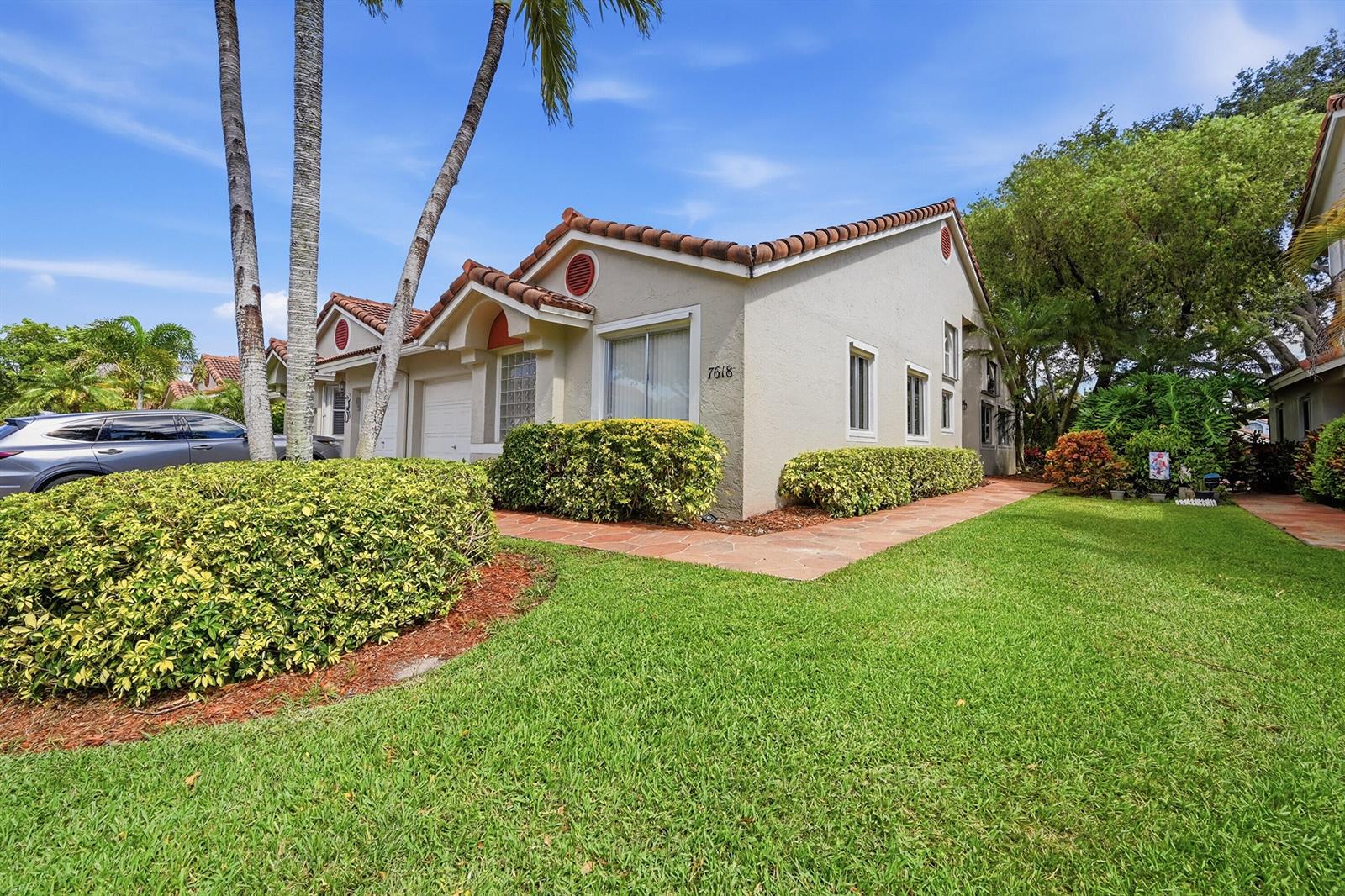 A single-story stucco house with a tile roof, palm trees, and a landscaped front yard — 7618 S Pinewalk Dr S # 132, Margate FL 33063, MARGATE, FL