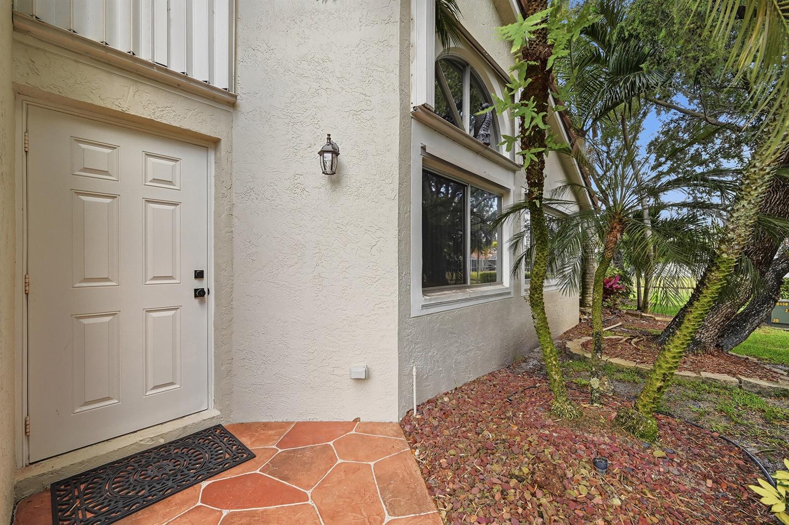 An exterior view of a home entrance with a white door and stone-tiled porch — 7618 S Pinewalk Dr S # 132, Margate FL 33063, MARGATE, FL