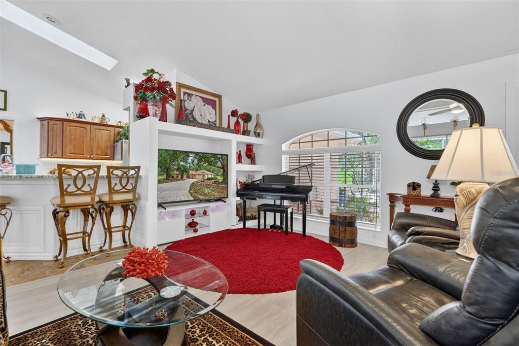 A living room features a white entertainment center, a black piano, and a red rug — 507 E GILCHRIST COURT, HERNANDO, FL