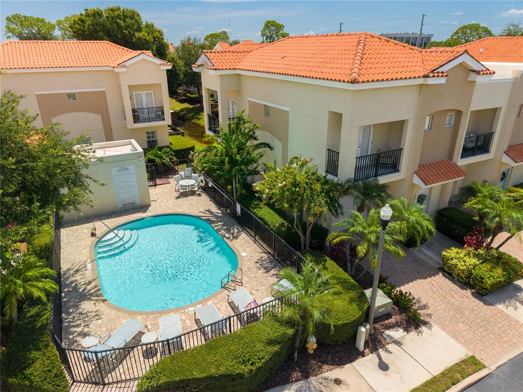 An aerial view shows a community swimming pool surrounded by a patio and residential buildings — 10015 6TH STREET N, ST PETERSBURG, FL