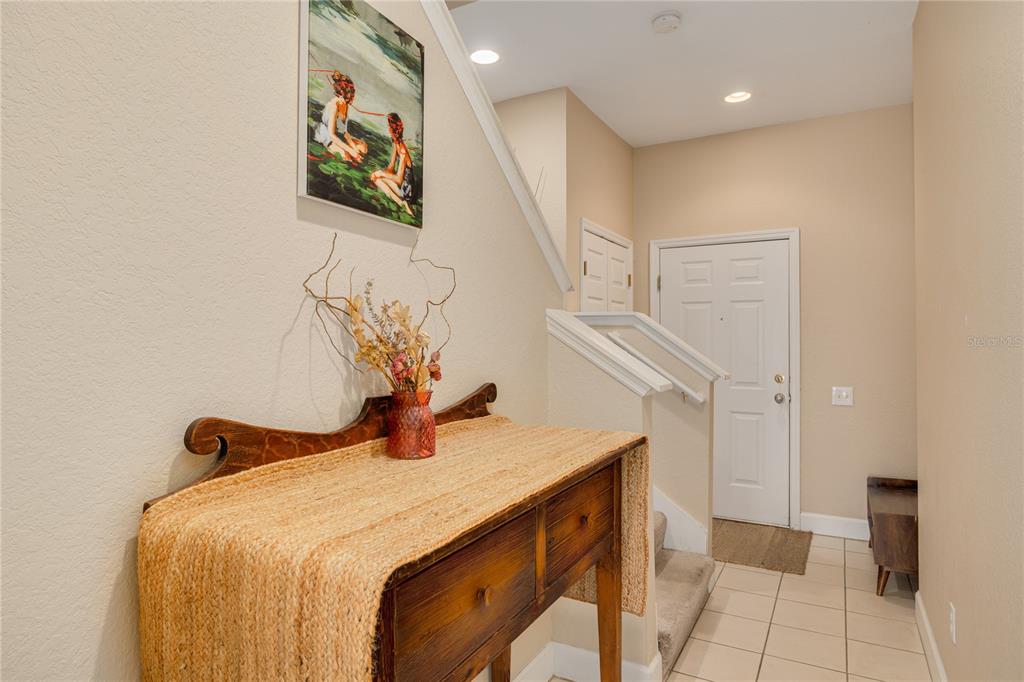 An entryway features a wooden console table, a wall painting, and stairs leading upward — 10015 6TH STREET N, ST PETERSBURG, FL