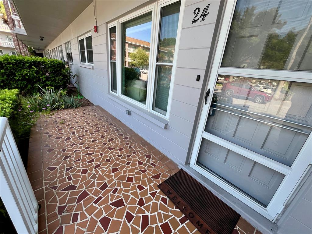 An exterior view of a building entrance with a mosaic-tiled porch and a front door — 2460 PERSIAN DRIVE UNIT 24, CLEARWATER, FL