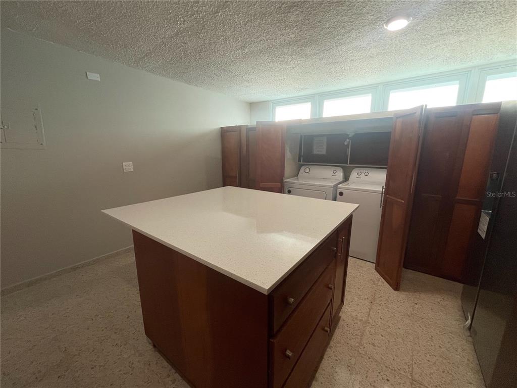 A laundry room features a central island with a white countertop and wooden cabinets — URB. VALLE REAL, INFANTA ST. UNIT 1826, PONCE, PR
