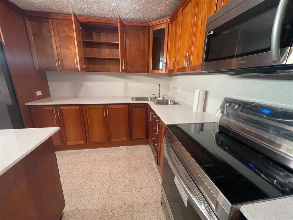 A kitchen features wood cabinets, white countertops, stainless steel appliances, and a tiled floor — URB. VALLE REAL, INFANTA ST. UNIT 1826, PONCE, PR