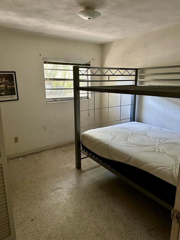 A bedroom features a metal bunk bed, a window, and light-colored speckled flooring — 1918 MOUNTAIN LAKE CUTOFF ROAD, LAKE WALES, FL