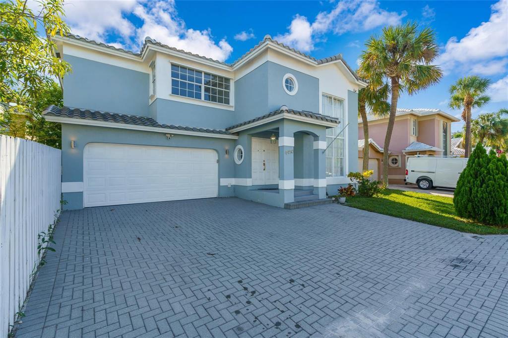 A two-story blue house with a paved driveway, a two-car garage, and a white fence — 4450 NW 55th Drive, Coconut Creek FL 33073, COCONUT CREEK, FL