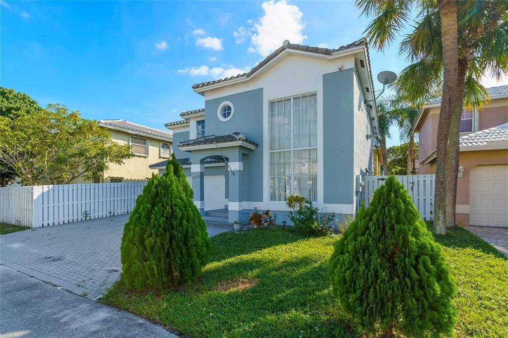 A two-story blue house with a paved driveway, two cone-shaped bushes, and a palm tree — 4450 NW 55th Drive, Coconut Creek FL 33073, COCONUT CREEK, FL