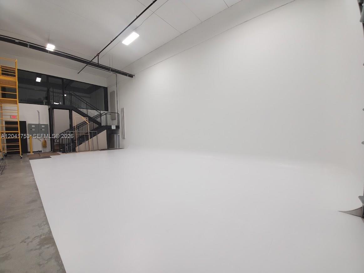 A large, empty white studio space features a curved wall, concrete floor, and metal staircase — 2017 NW 135 Avenue, Miami FL 33182, MIAMI, FL