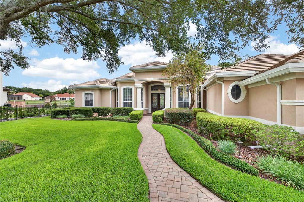 A single-story house with a beige stucco exterior, tile roof, and a brick paver walkway — 1911 BELFORD COURT, MAITLAND, FL
