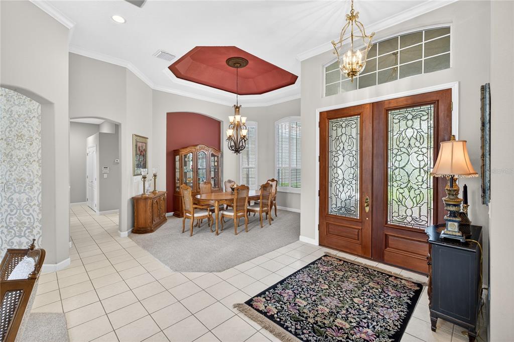 A foyer with tile flooring leads into a carpeted dining room featuring a tray ceiling — 1911 BELFORD COURT, MAITLAND, FL
