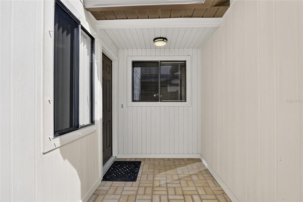 A covered entryway features white vertical siding, a dark front door, and a tiled floor — 367 CASTLEWOOD LANE, NEW SMYRNA BEACH, FL