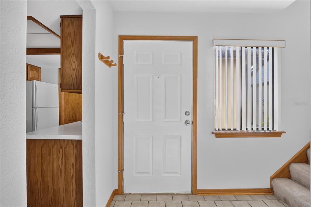 An entryway features a white front door, tiled floor, a window with blinds, and stairs — 367 CASTLEWOOD LANE, NEW SMYRNA BEACH, FL