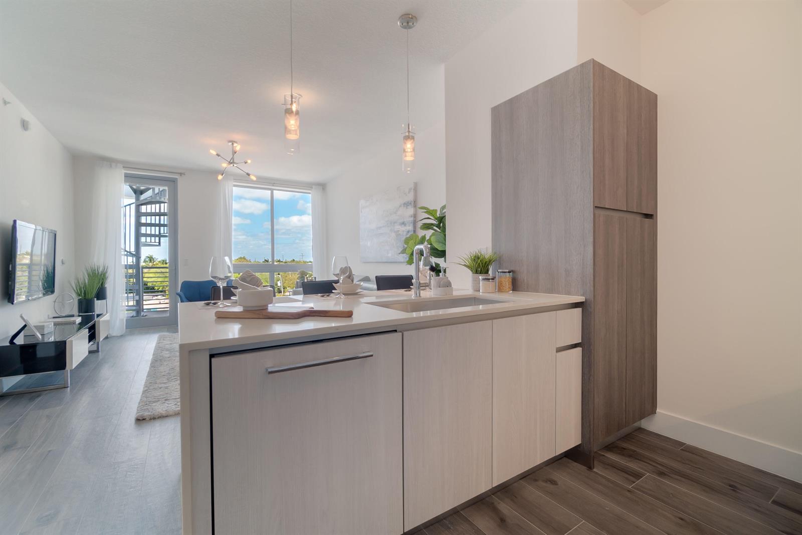 A modern kitchen island with a sink sits in an open-concept living space — 111 SE 1st Avenue # 512, Delray Beach FL 33444, DELRAY BEACH, FL