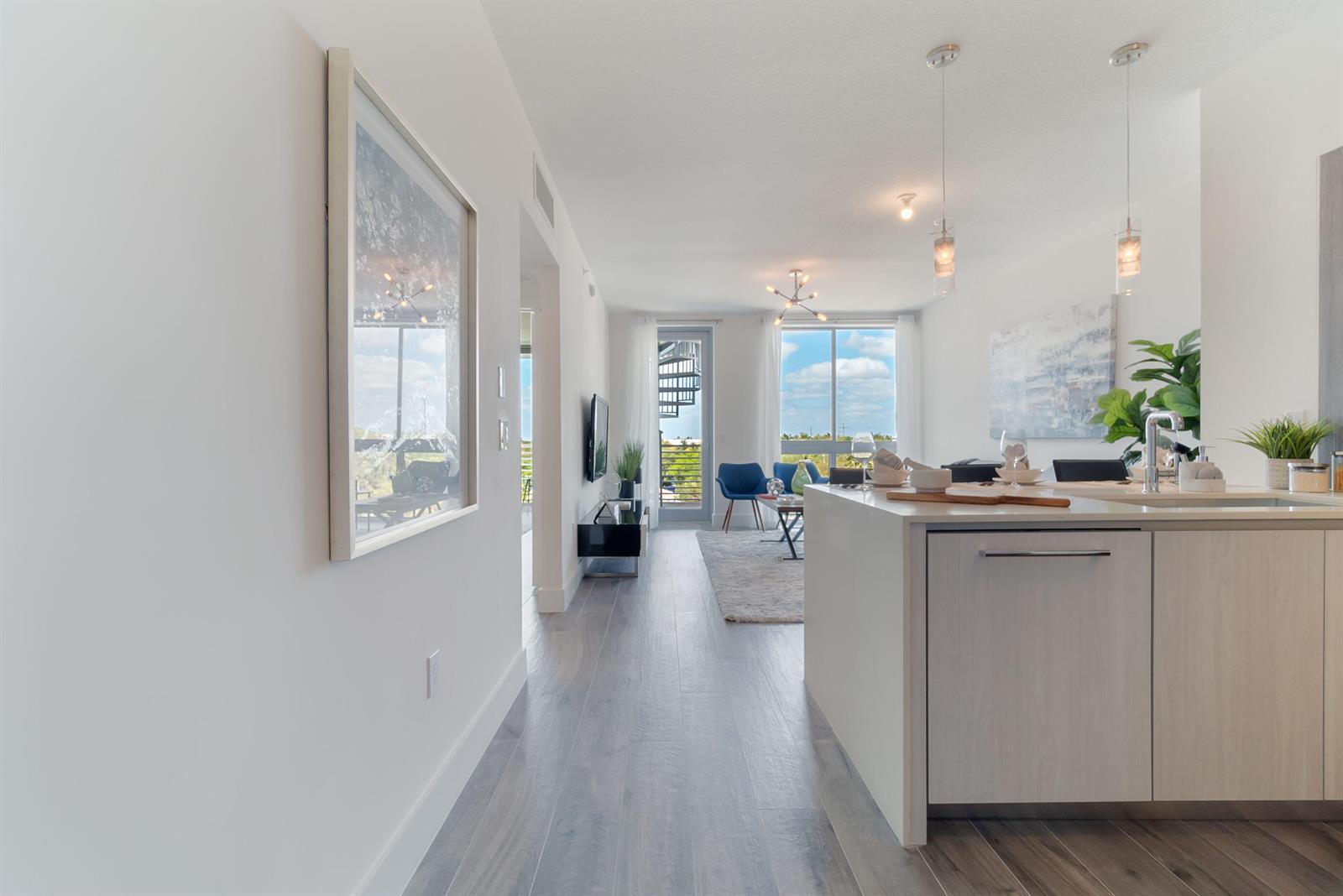 A modern kitchen island overlooks a living area with a spiral staircase visible outside — 111 SE 1st Avenue # 512, Delray Beach FL 33444, DELRAY BEACH, FL