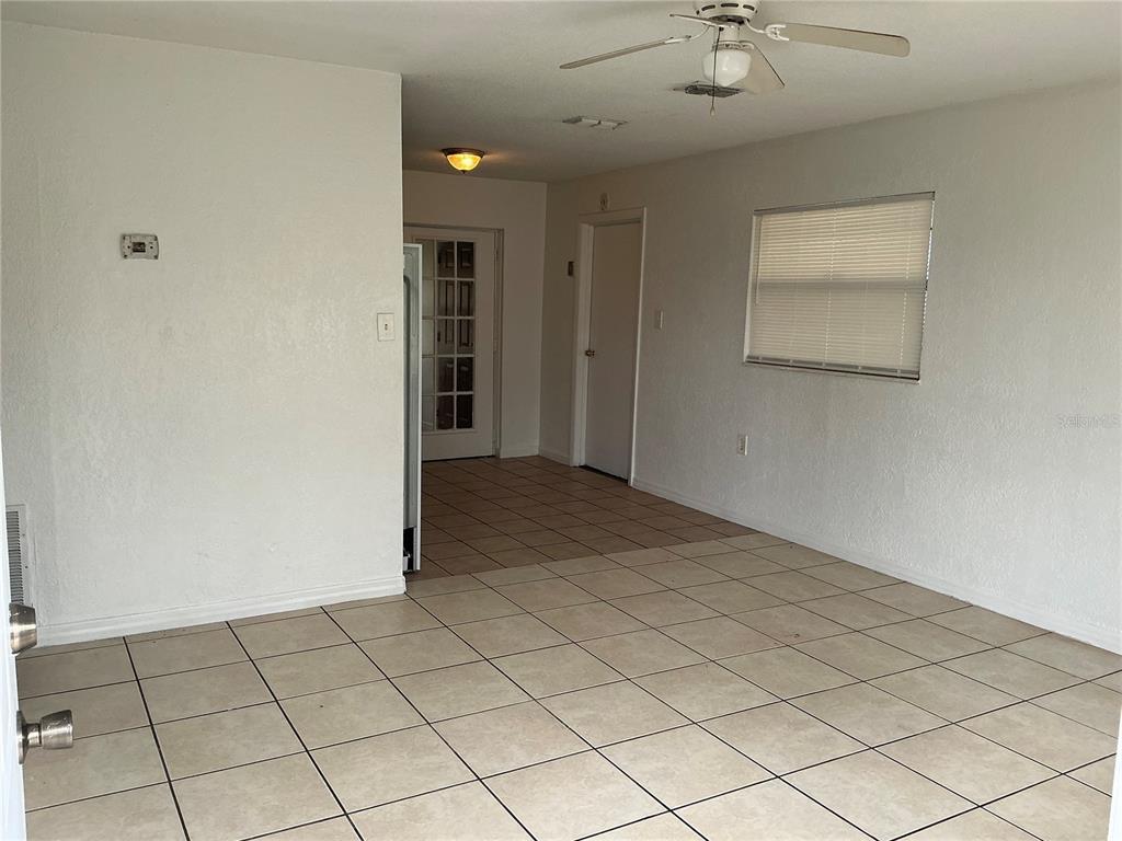 A room with beige tile flooring, white walls, a ceiling fan, and a doorway — 5132 ELESE STREET, ORLANDO, FL