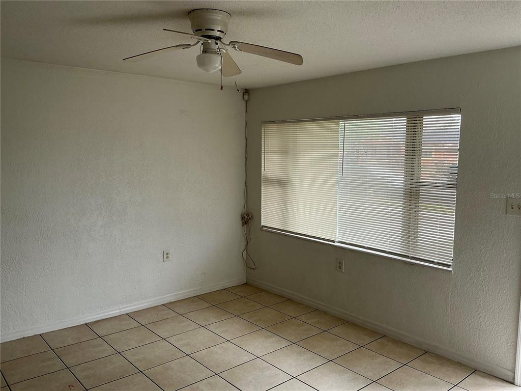 An empty room features white walls, a ceiling fan, and light-colored square floor tiles — 5132 ELESE STREET, ORLANDO, FL