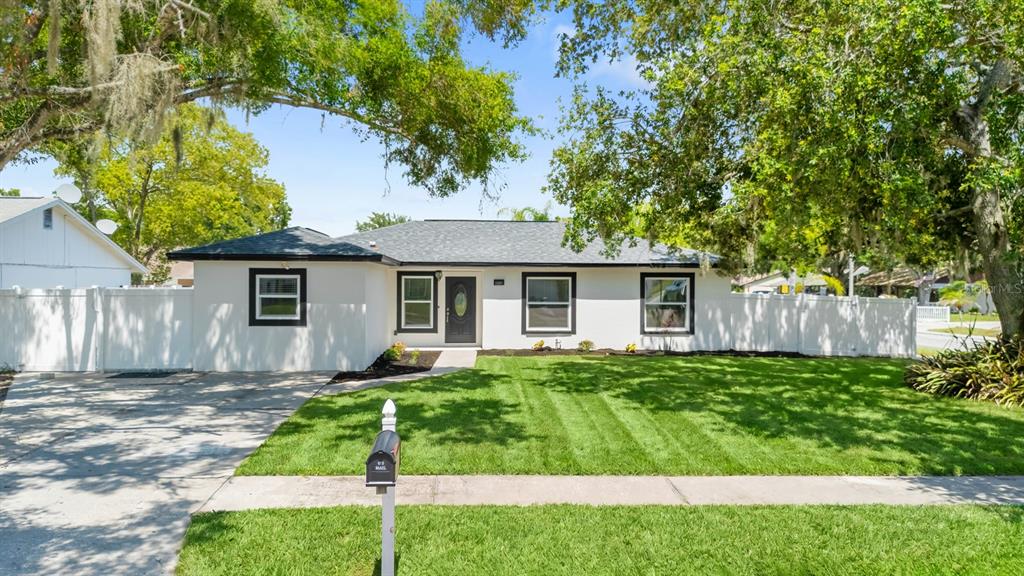 A single-story house with a white exterior, dark trim, and a front lawn — 1201 WINDY RIDGE DRIVE, BRANDON, FL
