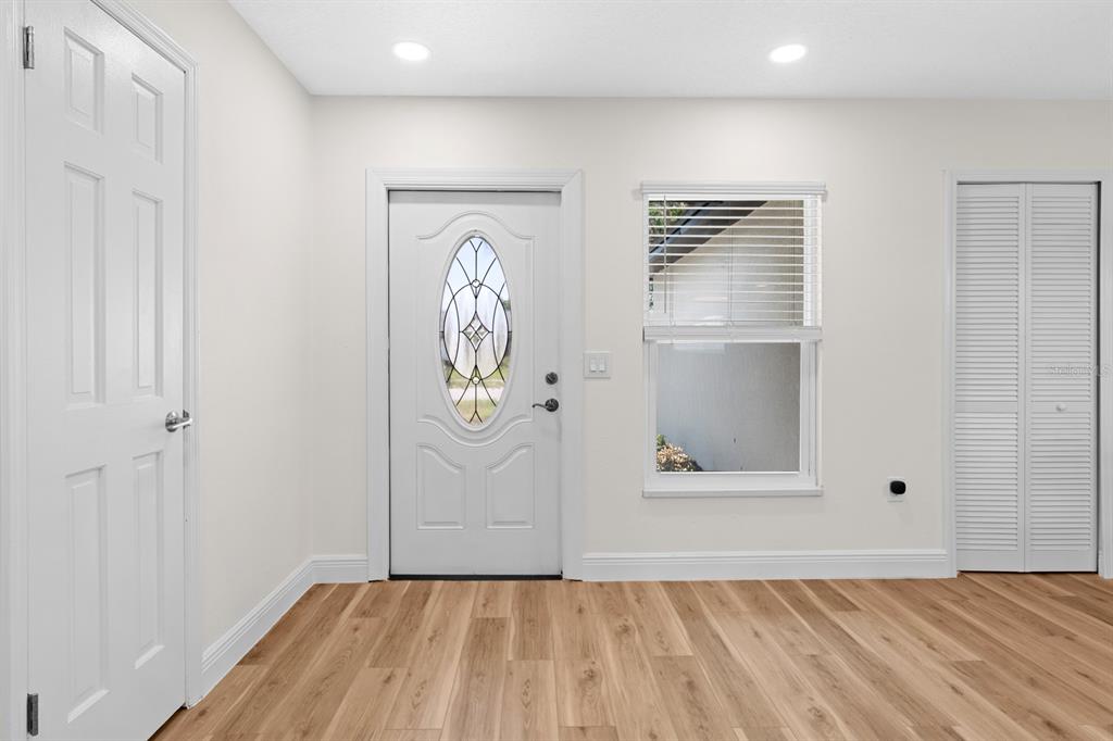An entryway features light wood-look flooring, a white front door with a glass insert, and closets — 1201 WINDY RIDGE DRIVE, BRANDON, FL