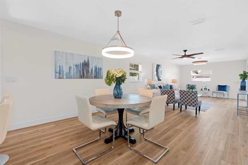 A dining area with a round table and chairs opens into a living room space — 1201 WINDY RIDGE DRIVE, BRANDON, FL