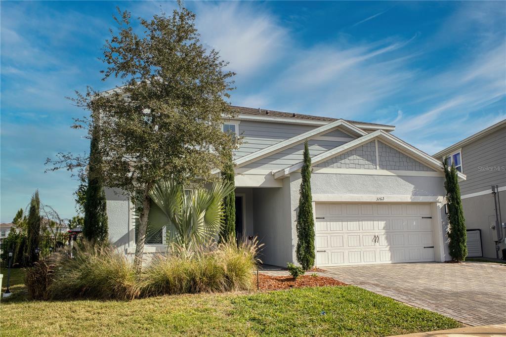 A two-story house with light gray siding, a two-car garage, and a paved driveway — 3262 HANGING TIDE STREET, WINTER GARDEN, FL