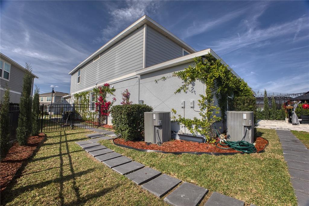 The side exterior of a two-story house features two HVAC units and a stone walkway — 3262 HANGING TIDE STREET, WINTER GARDEN, FL