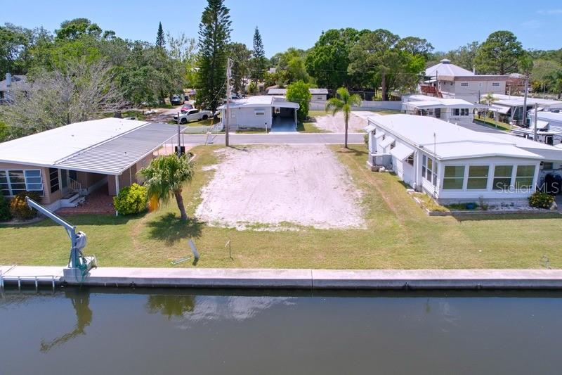 An aerial view shows a vacant waterfront lot situated between two mobile homes — 18 YAWL LANE UNIT 18, PALM HARBOR, FL
