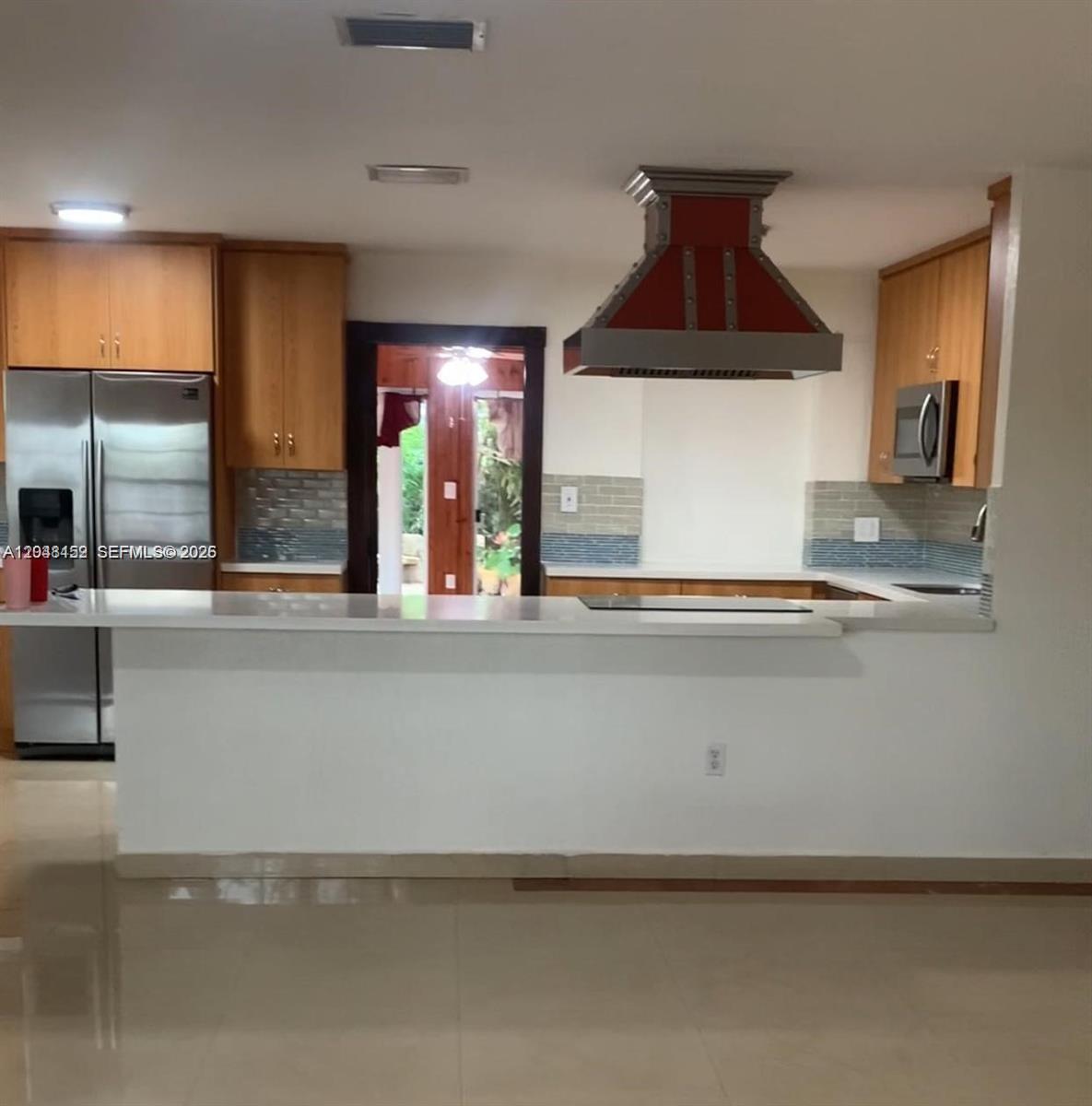 A kitchen features light wood cabinets, a white countertop, and a prominent red range hood — 10955 SW 56th St, Miami FL 33165, MIAMI, FL