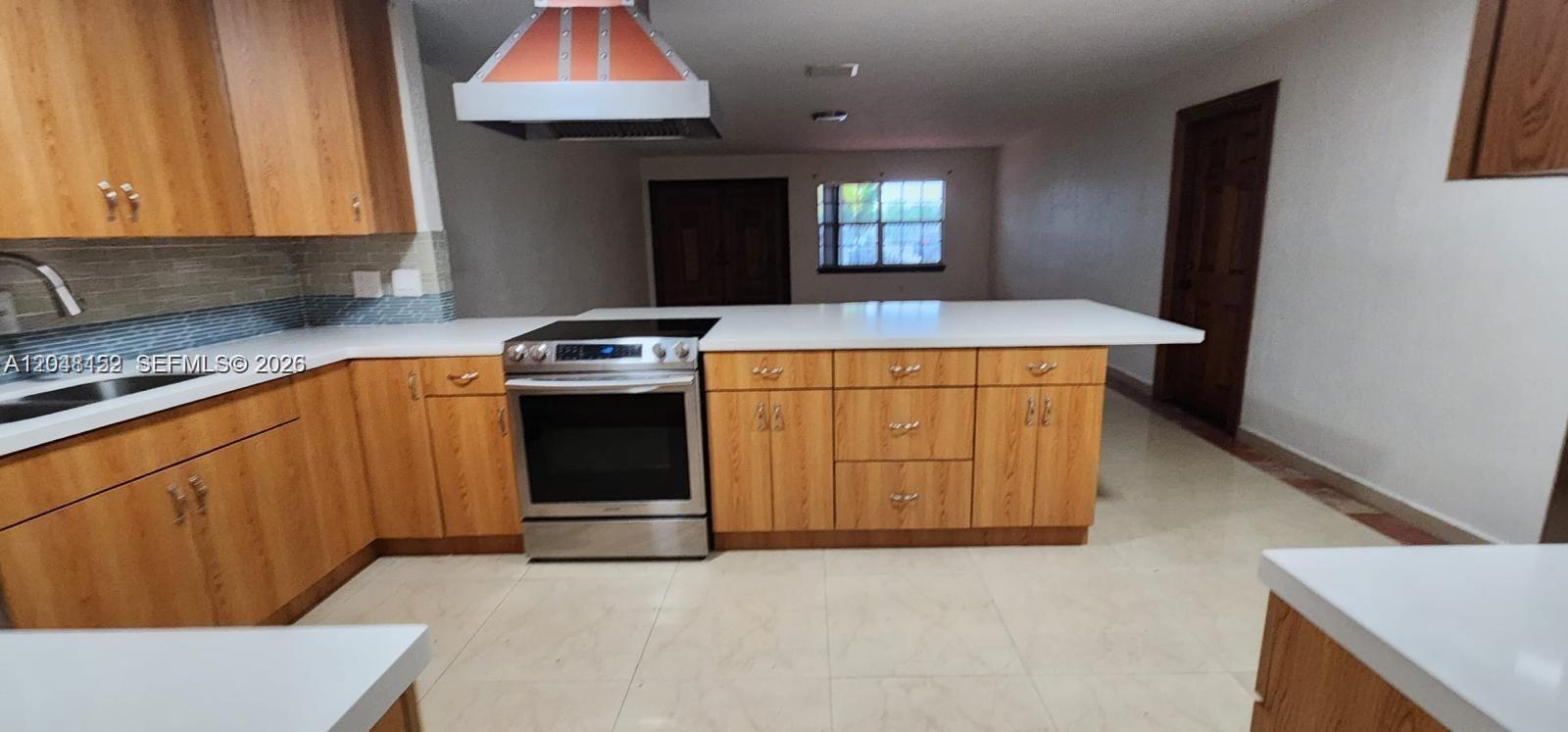 A kitchen features wood cabinets, a stainless steel stove, and a white countertop island — 10955 SW 56th St, Miami FL 33165, MIAMI, FL