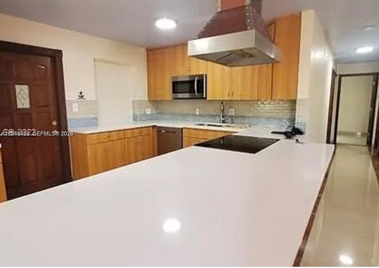 A kitchen features light wood cabinets, a white countertop island, and a stainless steel range hood — 10955 SW 56th St, Miami FL 33165, MIAMI, FL