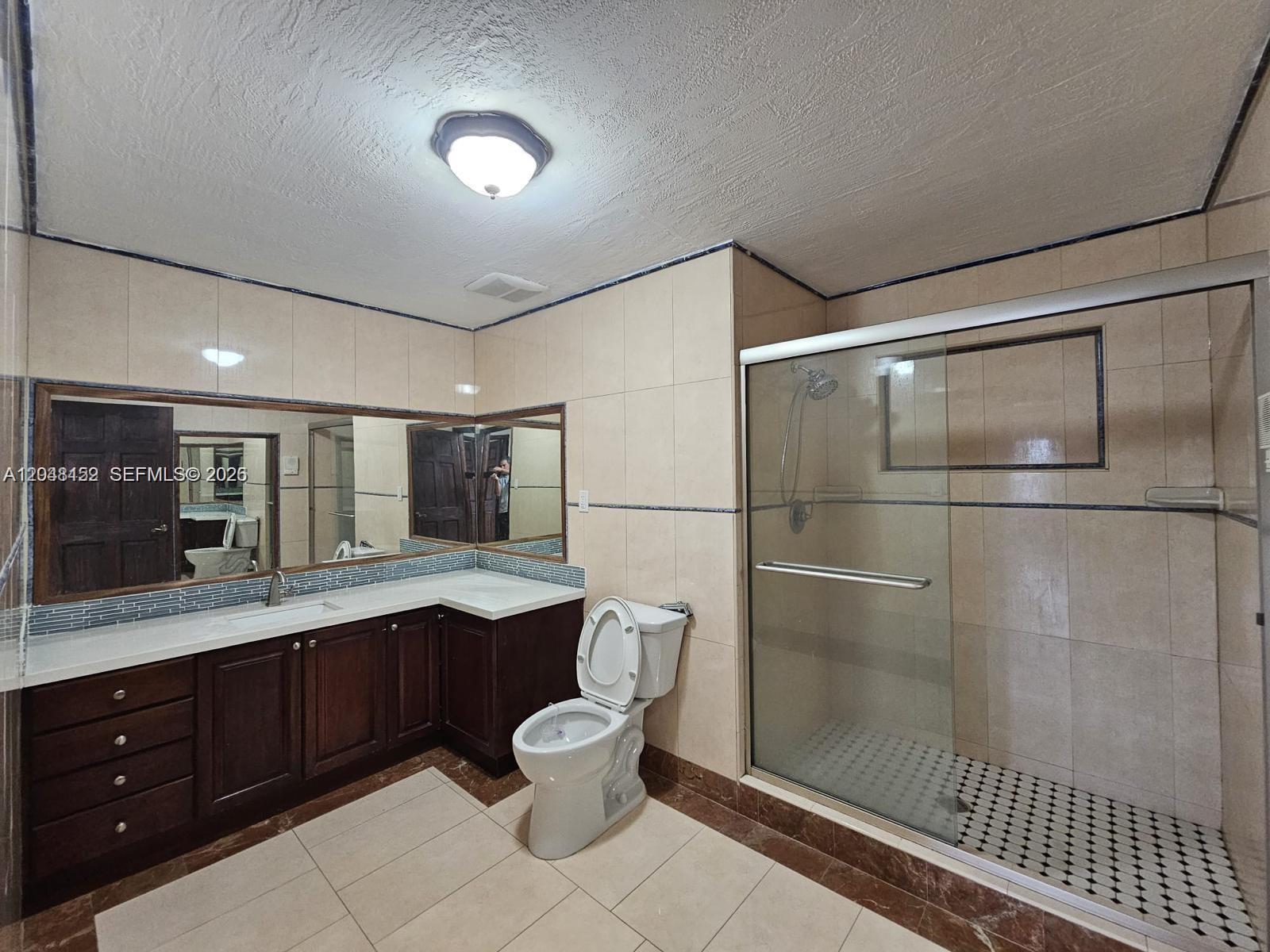 A bathroom features a dark wood vanity, a toilet, and a glass-enclosed walk-in shower — 10955 SW 56th St, Miami FL 33165, MIAMI, FL