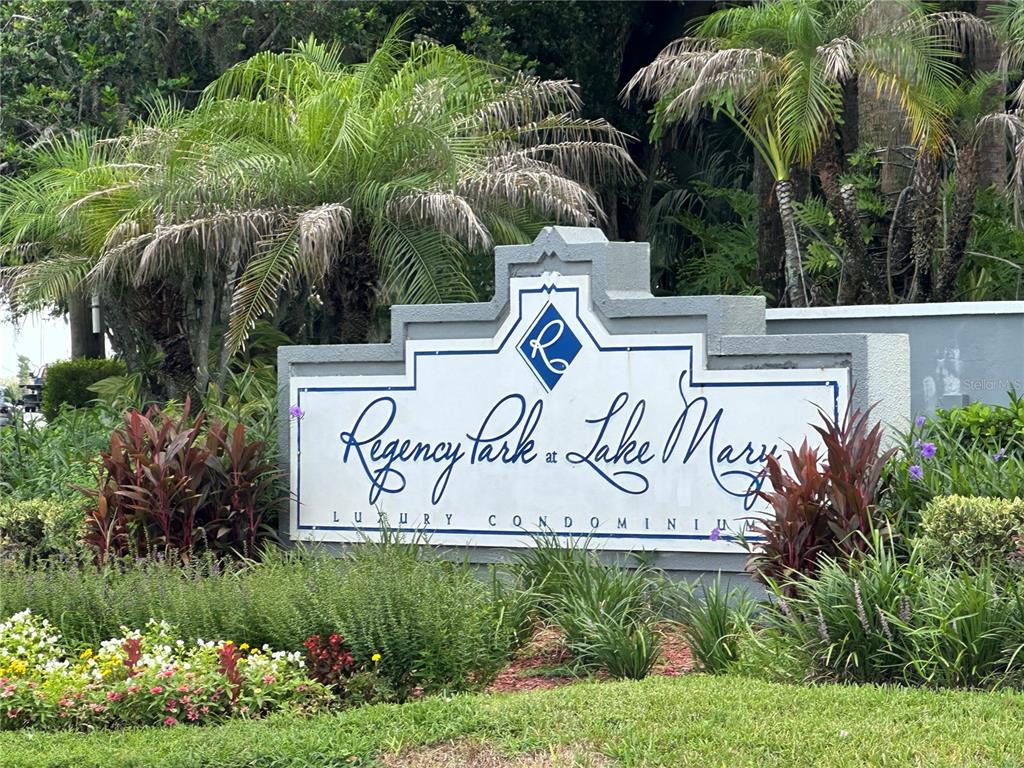 A sign for Regency Park at Lake Mary Luxury Condominiums stands in a landscaped garden — 709 SECRET HARBOR LANE UNIT 101, LAKE MARY, FL
