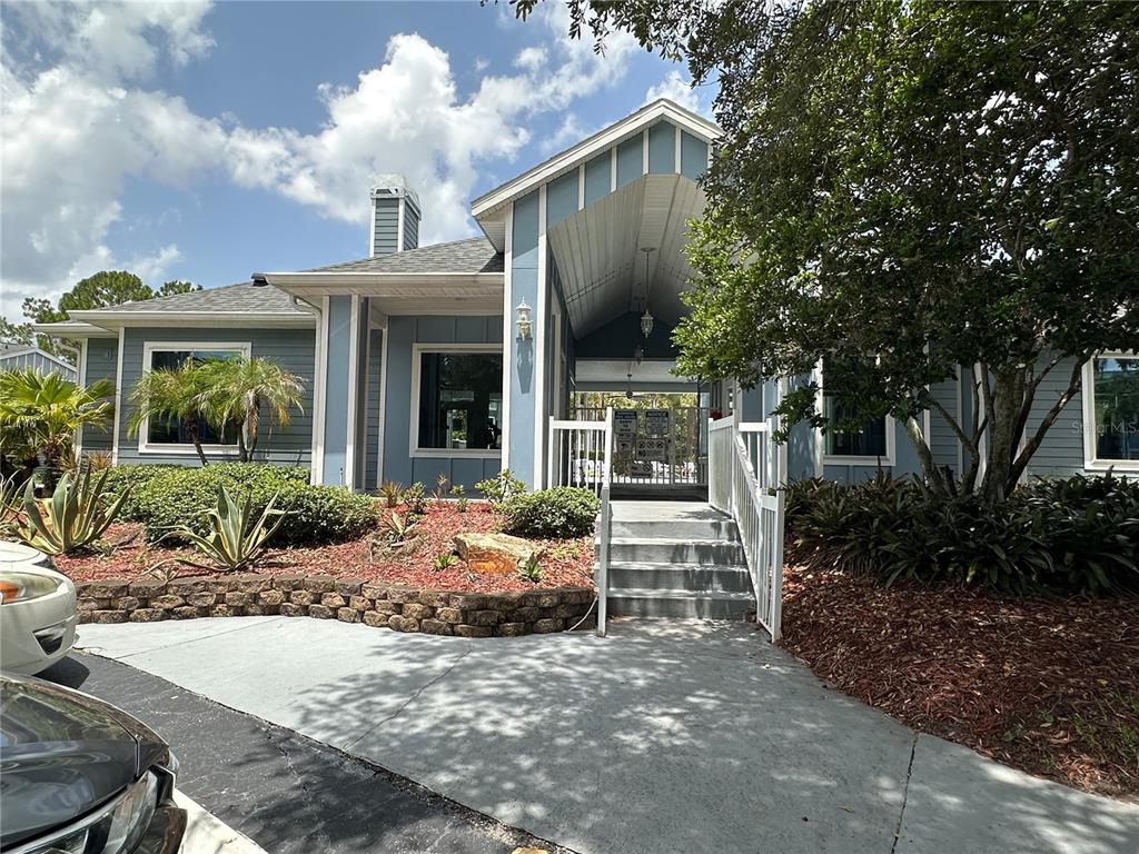 A blue-sided building features a covered entrance with stairs leading to a gated area — 709 SECRET HARBOR LANE UNIT 101, LAKE MARY, FL