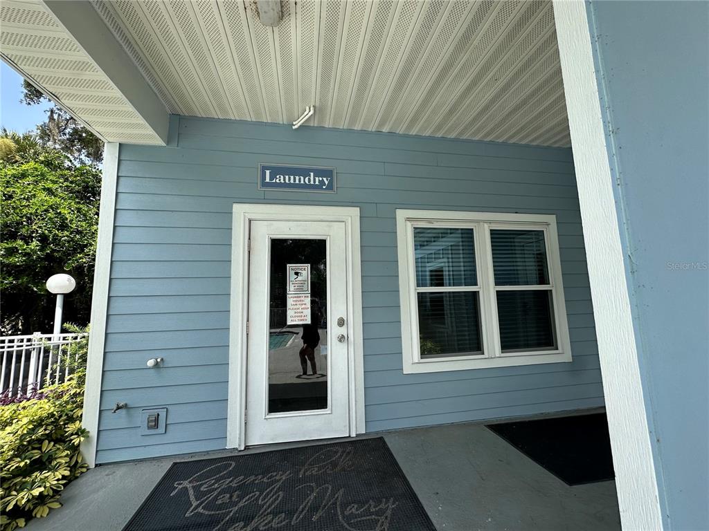The exterior of a light blue building features a laundry room door and a window — 709 SECRET HARBOR LANE UNIT 101, LAKE MARY, FL