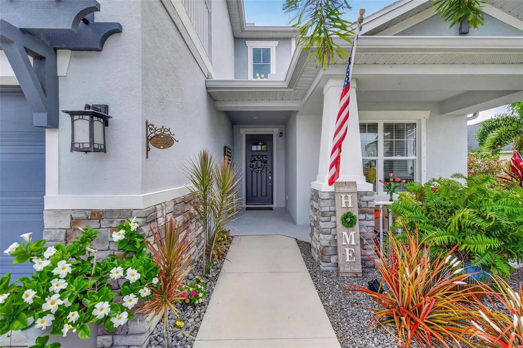 A front entrance features a stone-accented porch, a gray door, and a decorative home sign — 5636 MAIDENSTONE WAY, PALMETTO, FL