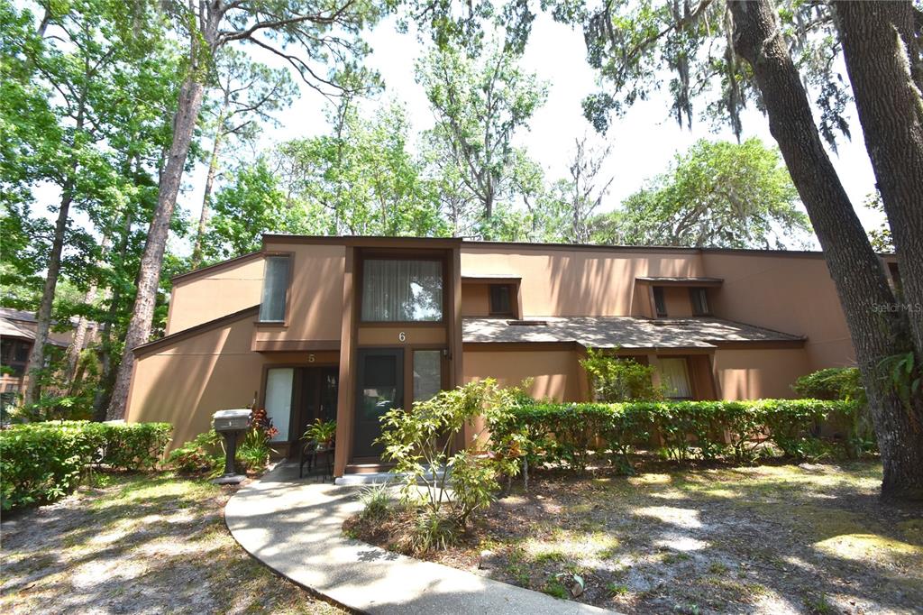 A two-story brown townhouse exterior features a concrete walkway leading to a central entrance — 6 BROADMORE CIRCLE UNIT 6, PALM COAST, FL
