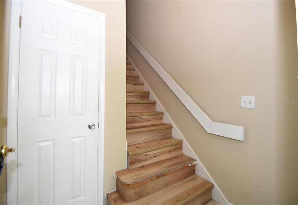 A staircase with wood treads and a white handrail sits beside a closed white door — 6 BROADMORE CIRCLE UNIT 6, PALM COAST, FL