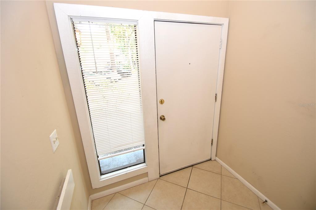 An entryway features a white door, a side window with blinds, and tiled flooring — 6 BROADMORE CIRCLE UNIT 6, PALM COAST, FL