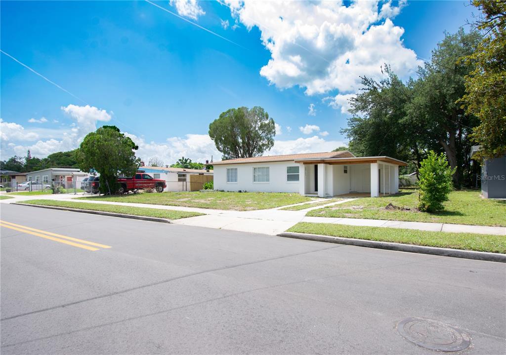 A single-story white house with a flat roof and a covered carport sits on a lot — 6146 DAHLIA DRIVE, ORLANDO, FL