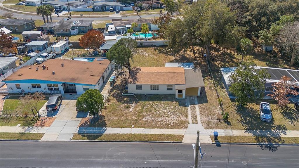 An aerial view shows three single-story houses with driveways and yards along a paved street — 6146 DAHLIA DRIVE, ORLANDO, FL