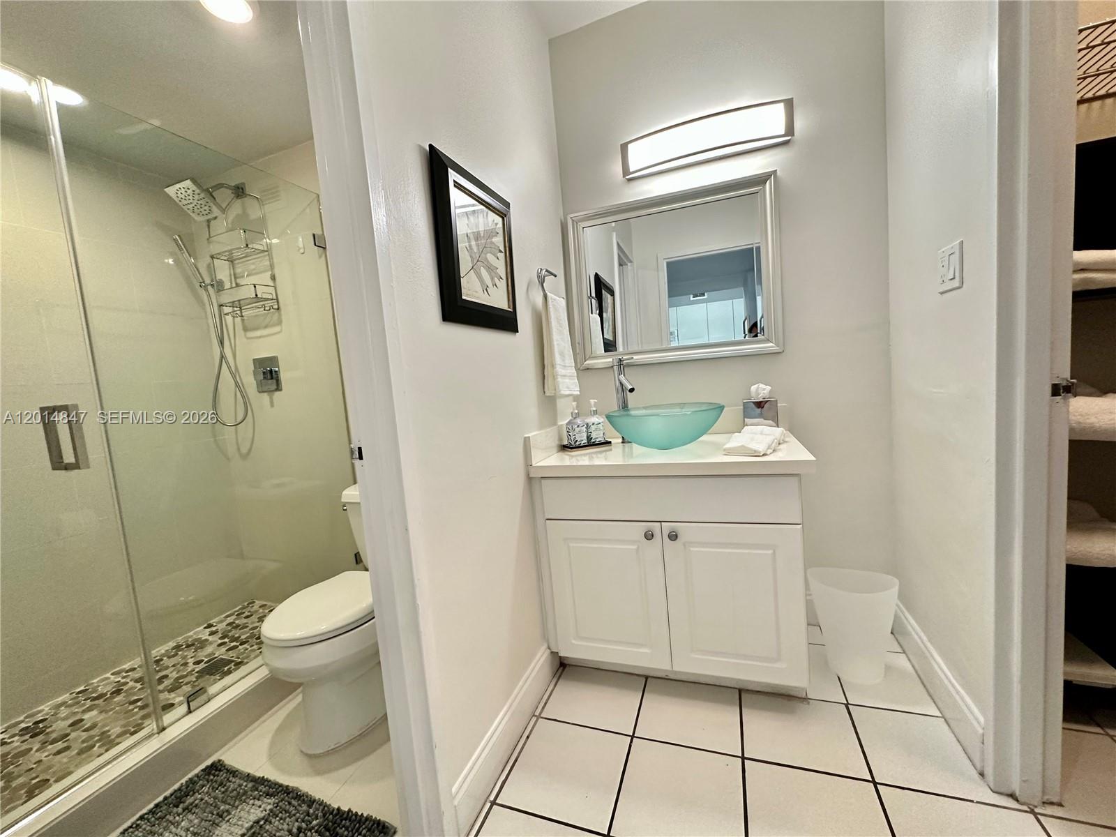 A bathroom features a glass vessel sink, a white vanity, and a glass-enclosed shower — 100 Lincoln Rd # 1012, Miami Beach FL 33139, MIAMI BEACH, FL
