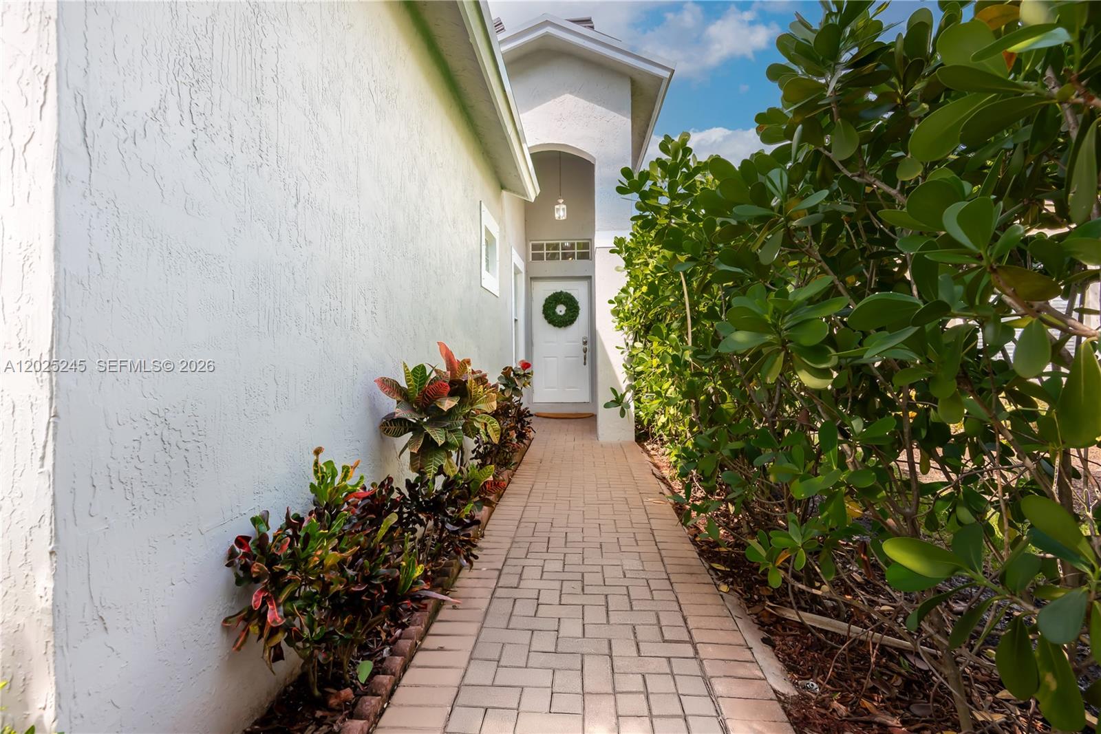 A paved walkway leads to a white front door framed by lush landscaping — 4123 Sapphire Bnd, Weston FL 33331, WESTON, FL