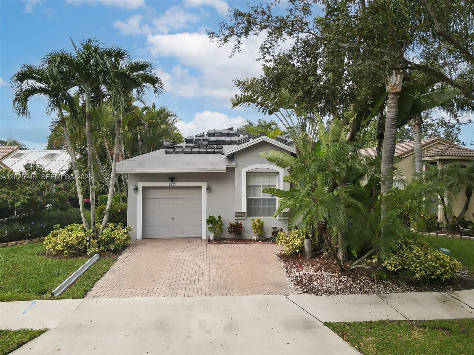 A single-story house with a gray exterior, a paved driveway, and a partially tiled roof — 4123 Sapphire Bnd, Weston FL 33331, WESTON, FL