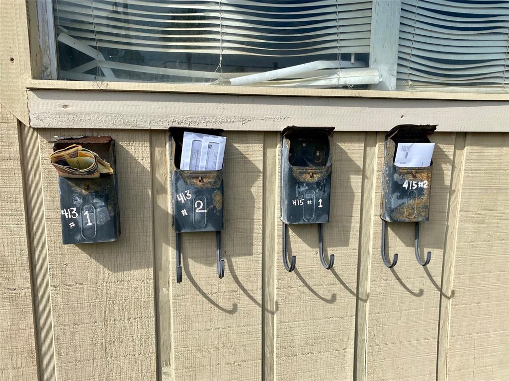 Four weathered, wall-mounted metal mailboxes are labeled with unit numbers and contain some mail — 415 VERMONT AVENUE, DAYTONA BEACH, FL