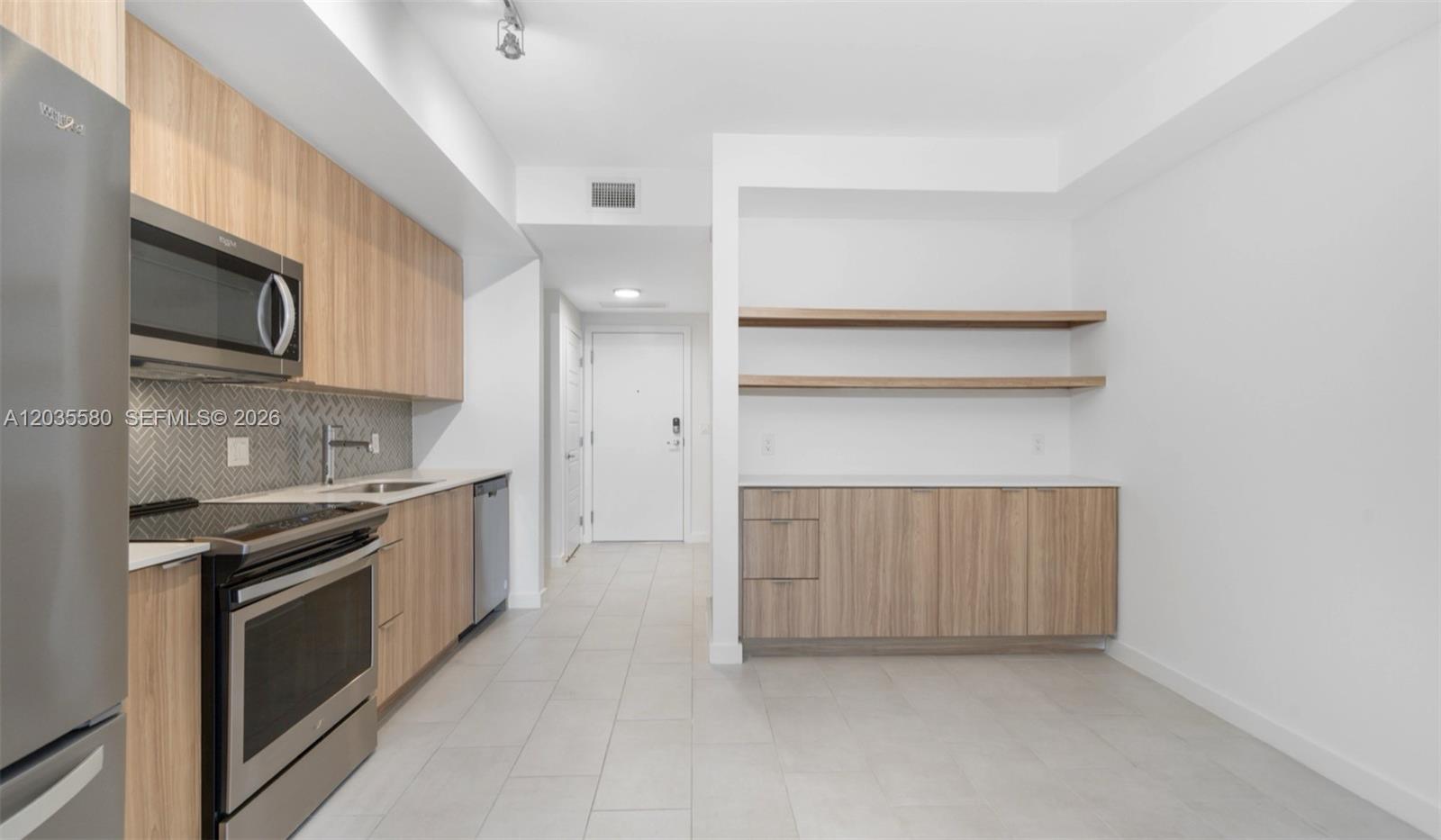 A modern kitchen features light wood cabinetry, stainless steel appliances, and open shelving — MIAMI, FL