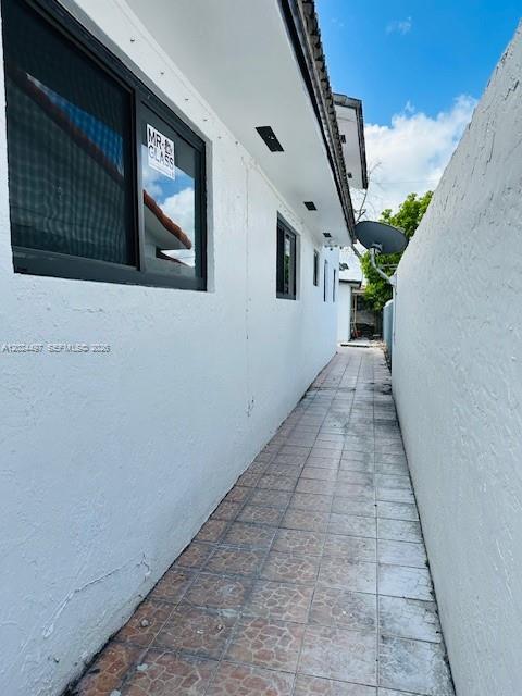 A narrow, tiled exterior walkway runs alongside a white building with a dark-framed window — 11870 SW 5th St # B, Miami FL 33184, MIAMI, FL