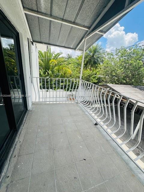A covered balcony with a white metal railing overlooks trees and a neighboring roof — 11870 SW 5th St # B, Miami FL 33184, MIAMI, FL