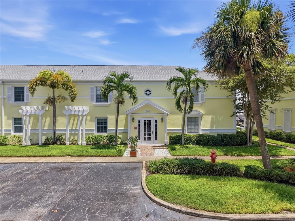 A two-story yellow building with white trim, palm trees, and a paved parking lot — 5092 BEACH DRIVE SE UNIT A, ST PETERSBURG, FL