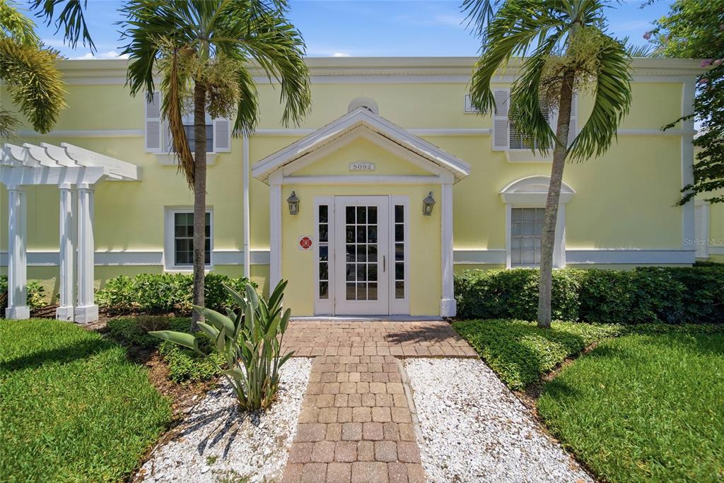 A yellow two-story building features a central white-framed entrance and a brick walkway — 5092 BEACH DRIVE SE UNIT A, ST PETERSBURG, FL
