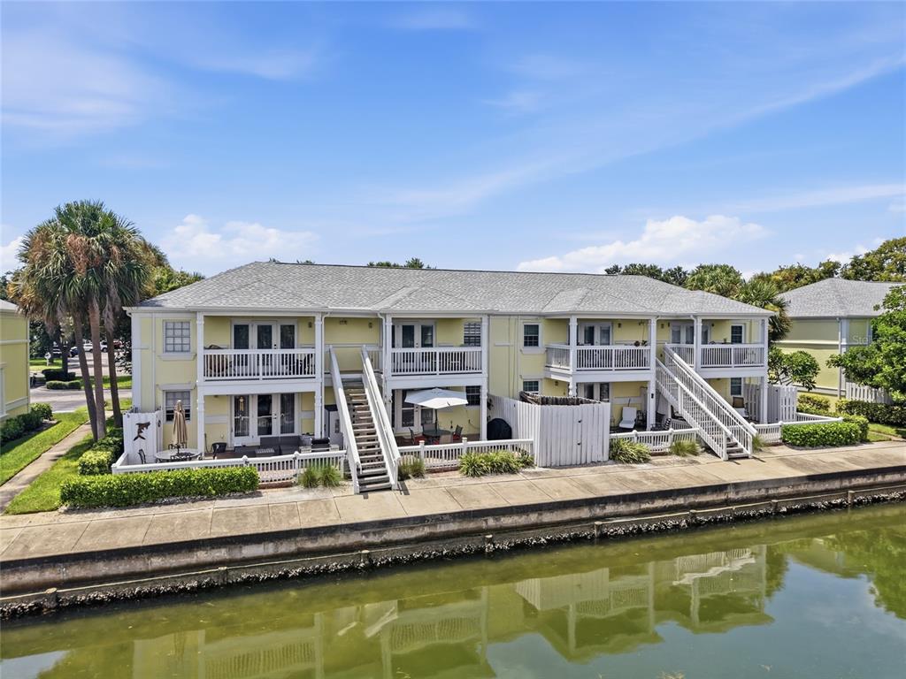 An exterior view of a two-story yellow apartment building situated along a canal — 5092 BEACH DRIVE SE UNIT A, ST PETERSBURG, FL