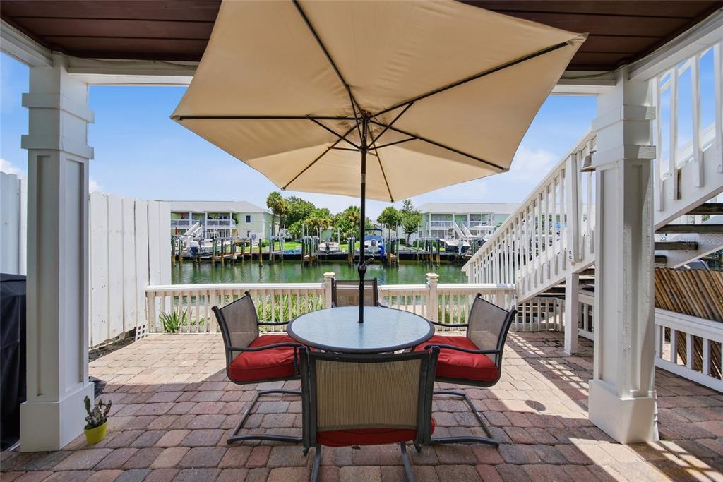 A paved patio with a dining set and umbrella overlooks a canal with boat slips — 5092 BEACH DRIVE SE UNIT A, ST PETERSBURG, FL